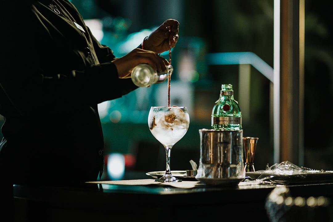 A bartender carefully pouring a signature cocktail at a Tokyo rooftop bar, the city lights reflecting through the glass.