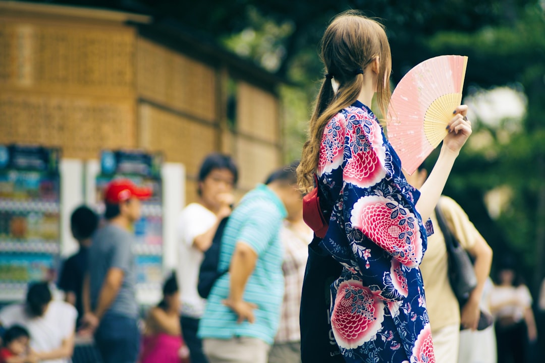 A woman in Tokyo uses a traditional folding fan to stay cool on a hot summer day, a simple ritual that works beautifully.