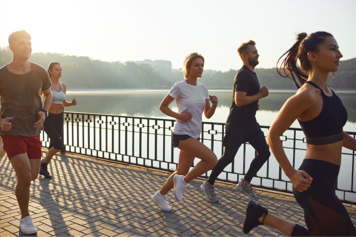 A group of runners at different paces gathering at a Tokyo running club meetup in Yoyogi Park at sunrise