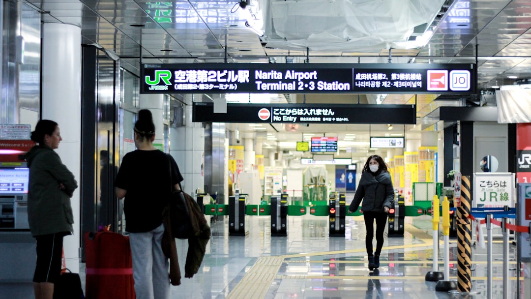 A traveller reviews their boarding pass at a Tokyo airport departure gate, aware of the departure tax added to their ticket.