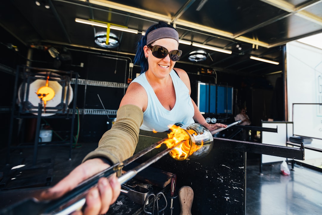 A woman works with molten glass during workshop