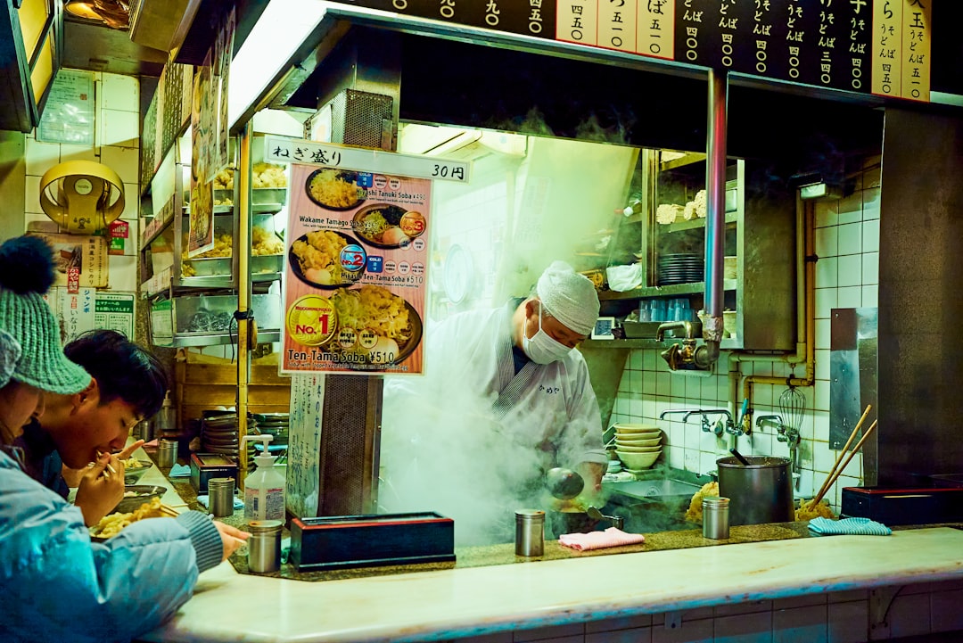 People in a Tokyo soba restaurant, dipping the chilled buckwheat noodles into a ceramic cup of dashi sauce.