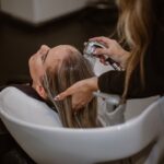 A woman relaxing during a scalp treatment at a Tokyo hair salon, eyes closed as a therapist works gently on her scalp